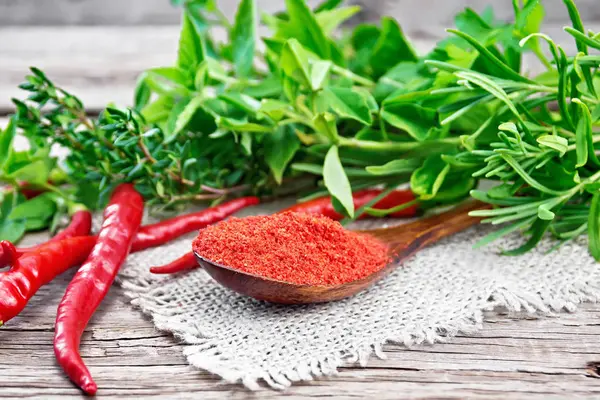 Peppers red powder in wooden spoon on old board — Stock Photo, Image