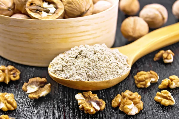 Flour walnut in spoon on black wooden board — Stok fotoğraf