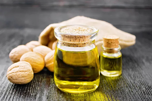 Oil walnut in jar and bottle on board — Stock Photo, Image