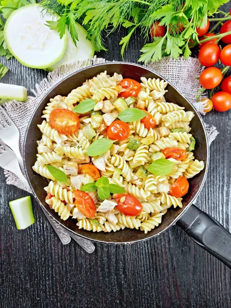 Fusilli with chicken and tomatoes in pan on black board top — Stock Photo, Image