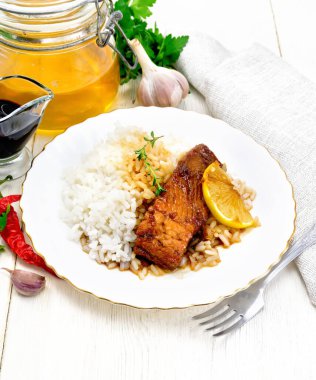 Bal, limon suyu ve soya soslu pembe somon, haşlanmış pirinç, bir tabak limon ve kekik dilimi, acı biber, sarımsak, maydanoz, havlu ve çatal arkaplandaki hafif ahşap tahta