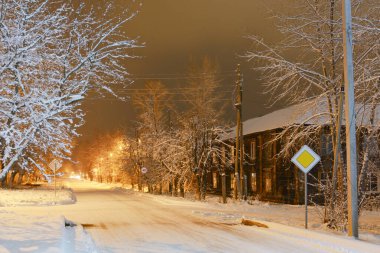 Gece aydınlığında kış sokağı. Önünde eski bir ev var.