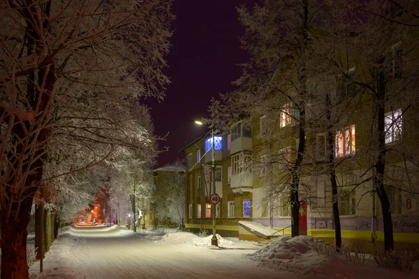 Night street with snowy trees in the light of lanterns and windows of houses, painted in different colors. — Stock Photo, Image