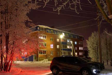 Gece sokağı evin pencerelerinden gelen kış ışıklarıyla aydınlanıyor..
