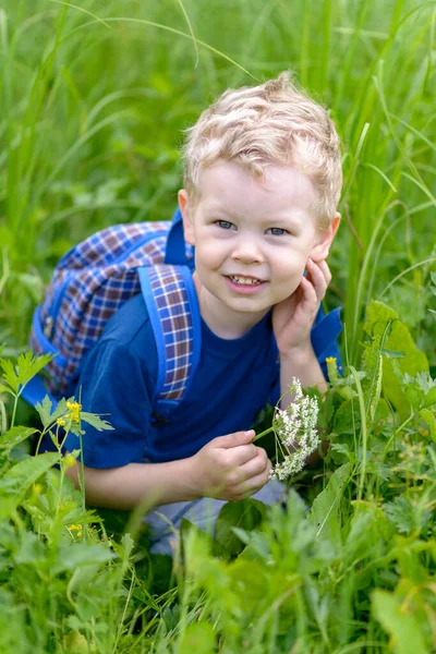 A little blond boy crouched in the green grass. — ストック写真