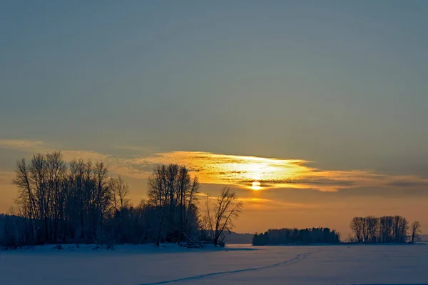 Orange low sun in a cloudy haze over a frozen river. — Stock Photo, Image