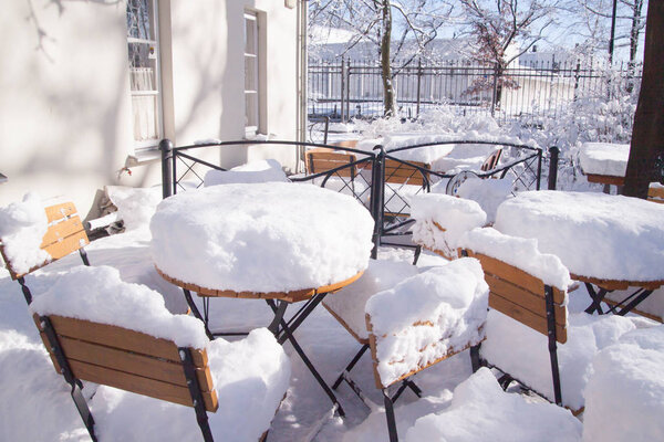 Tables and chairs near building entrance covered with heavy layer of snow, Warsaw, Poland