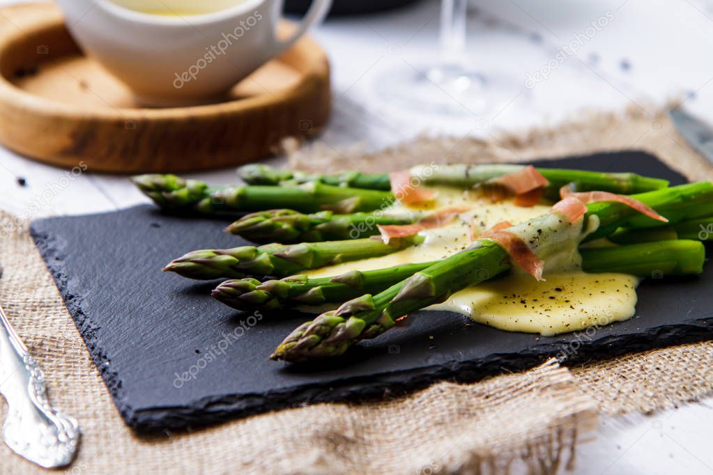 Asparagus with Dutch sauce and Parma ham. Serving close up