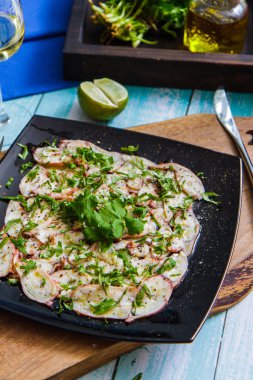 Kare siyah bir plaka üzerinde bir ahtapot carpaccio. İtalyan mutfağı