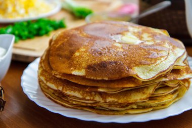 Krep yerken üzerine beyaz bir tabak, yeşil soğan ve ekşi krema tablo yan görünüm