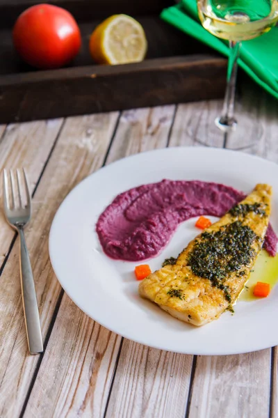 Fried fish, beet pulp and a glass of wine on old boards