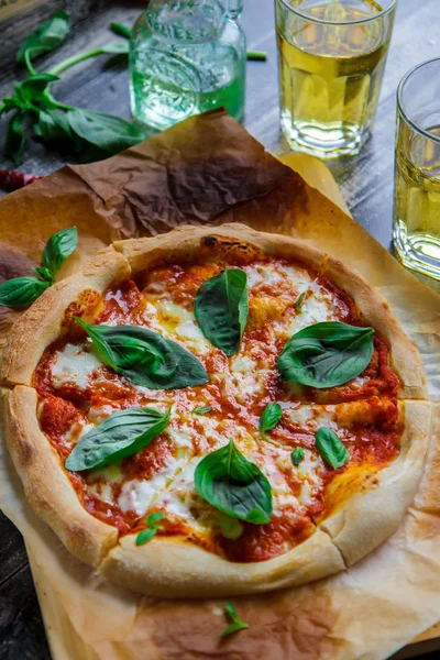 Pizza margarita on parchment, glasses with juice