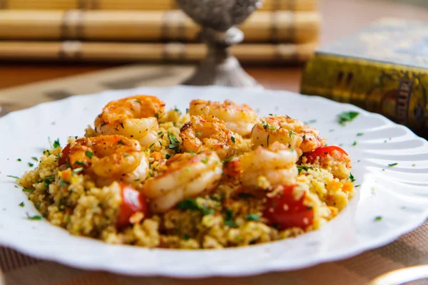 Couscous met garnalen en groenten in een bord Stockfoto