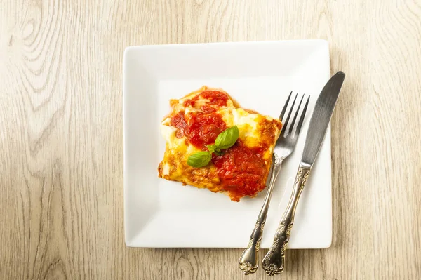 Portion appétissante de lasagnes sur une assiette blanche avec sauce tomate — Photo