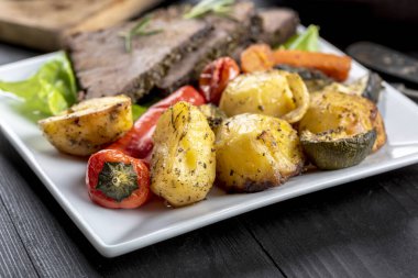 Ev yapımı yemek. Pişmiş sebzelerle çevrili taze otlarla kızartılmış biftek.