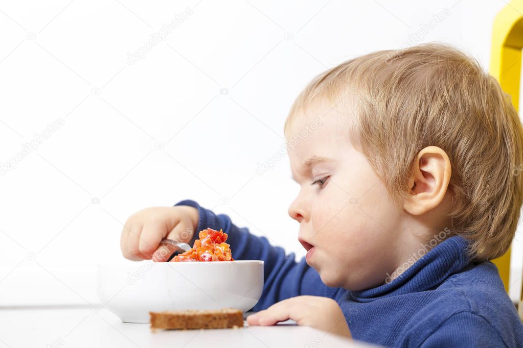 Baby eats vegetable soup spoon