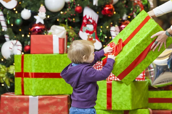 Mom gives a gift to the kid on the background of the Christmas — Stock Photo, Image
