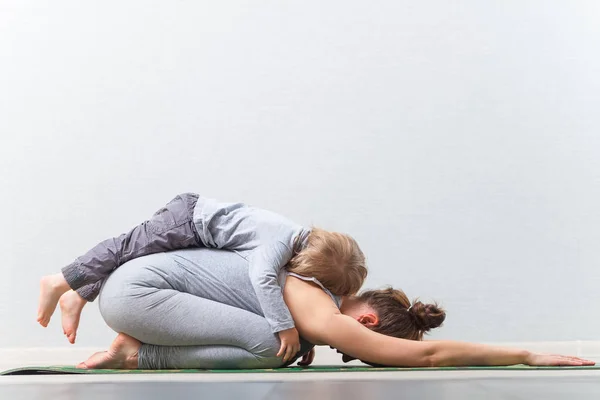 Hatha yoga fitness moeder met baby. — Stockfoto