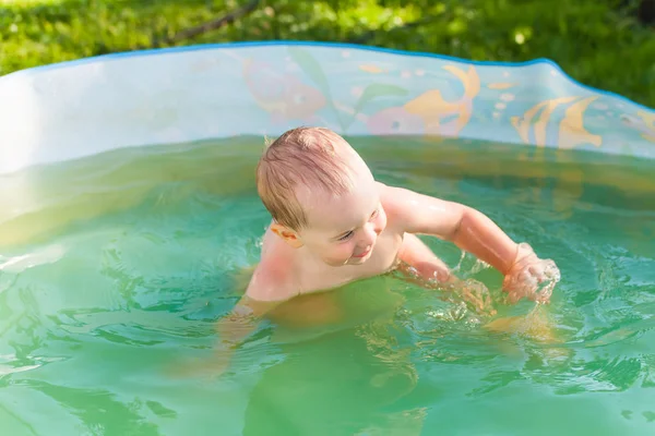 Baby schwimmt in einem Plastikbecken in der Natur — Stockfoto