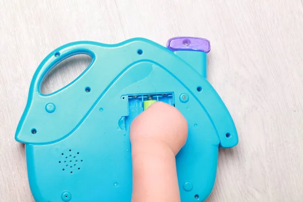 Mão a criança colocar as baterias no brinquedo vermelho — Fotografia de Stock