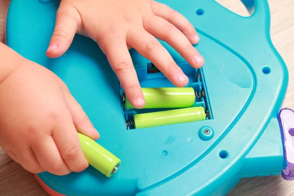 Hand legte das Kind die Batterien in das rote Spielzeug — Stockfoto