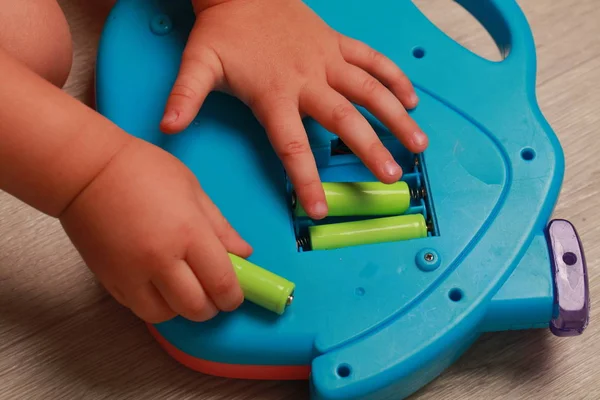 Hand legte das Kind die Batterien in das rote Spielzeug — Stockfoto