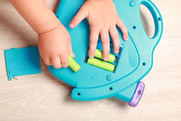 Hand legte das Kind die Batterien in das rote Spielzeug — Stockfoto