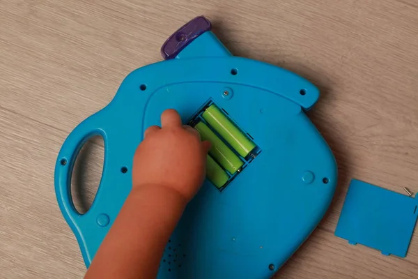 Рука ребенка положила батарейки в красную игрушку — стоковое фото