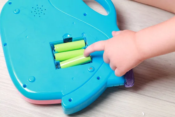Hand the child put the batteries in the red toy — Stock Photo, Image