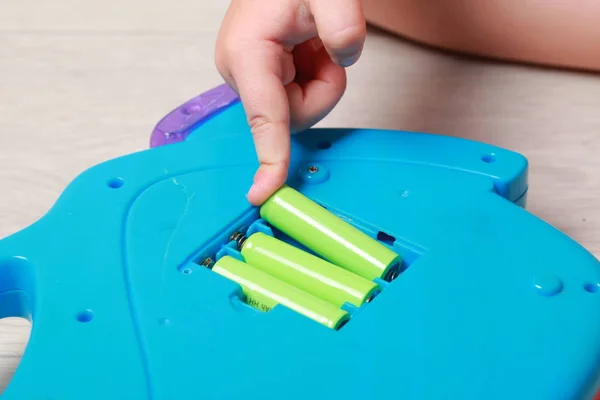 Рука ребенка положила батарейки в красную игрушку — стоковое фото
