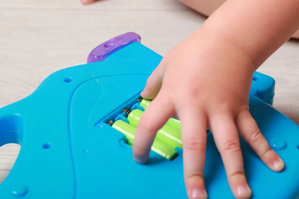 Hand the child put the batteries in the red toy — Stock Photo, Image