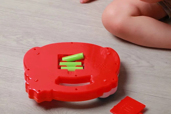 Rękę dziecko umieścić baterie w czerwony zabawka — Zdjęcie stockowe