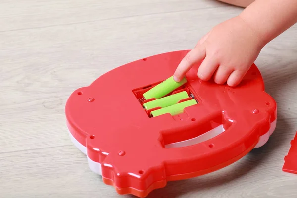Mano el niño puso las baterías en el juguete rojo — Foto de Stock