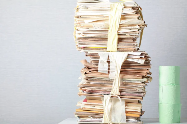 A stack of waste paper and a roll of toilet paper — Stock Photo, Image