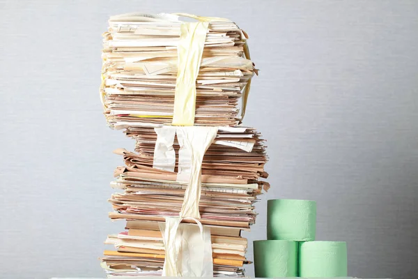 A stack of waste paper and a roll of toilet paper — Stock Photo, Image