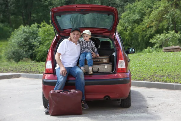 Un hombre y un niño cargan las maletas de su coche — Foto de Stock