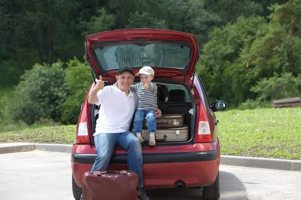 Un hombre y un niño cargan las maletas de su coche — Foto de Stock