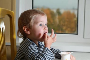 Komik bebek çocuk sarışın yalıyor parmak yoğurt ile