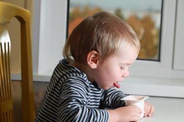 Komik bebek çocuk sarışın yalıyor parmak yoğurt ile
