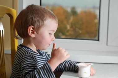 Komik bebek çocuk sarışın yalıyor parmak yoğurt ile