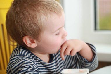 Komik bebek çocuk sarışın yalıyor parmak yoğurt ile