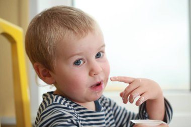 Komik bebek çocuk sarışın yalıyor parmak yoğurt ile