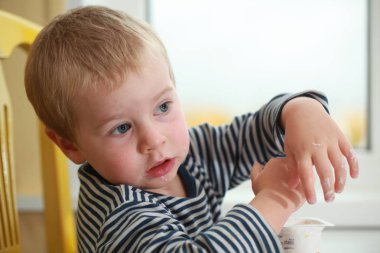 Komik bebek çocuk sarışın yalıyor parmak yoğurt ile