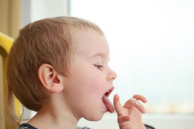 Komik bebek çocuk sarışın yalıyor parmak yoğurt ile