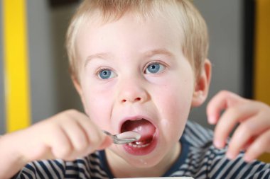 Komik bebek çocuk sarışın yalıyor parmak yoğurt ile