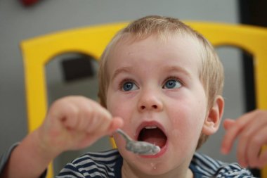 Komik bebek çocuk sarışın yalıyor parmak yoğurt ile