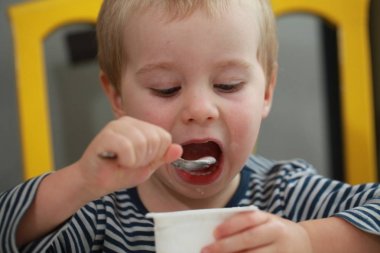 Komik bebek çocuk sarışın yalıyor parmak yoğurt ile