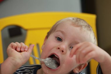 Komik bebek çocuk sarışın yalıyor parmak yoğurt ile