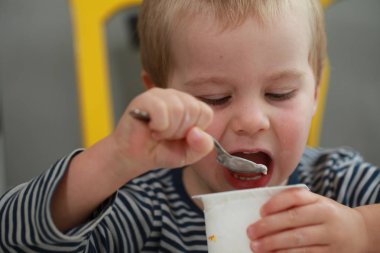 Komik bebek çocuk sarışın yalıyor parmak yoğurt ile