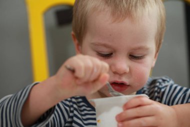 Komik bebek çocuk sarışın yalıyor parmak yoğurt ile